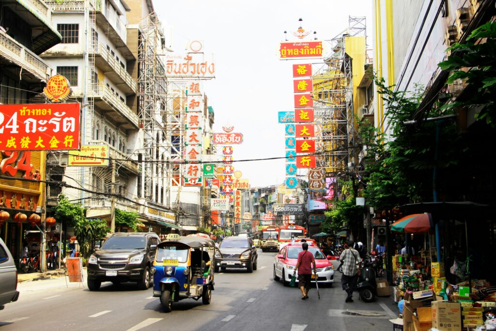 Busy street in Bangkok Chinatown with tuk tuk and colorful signs